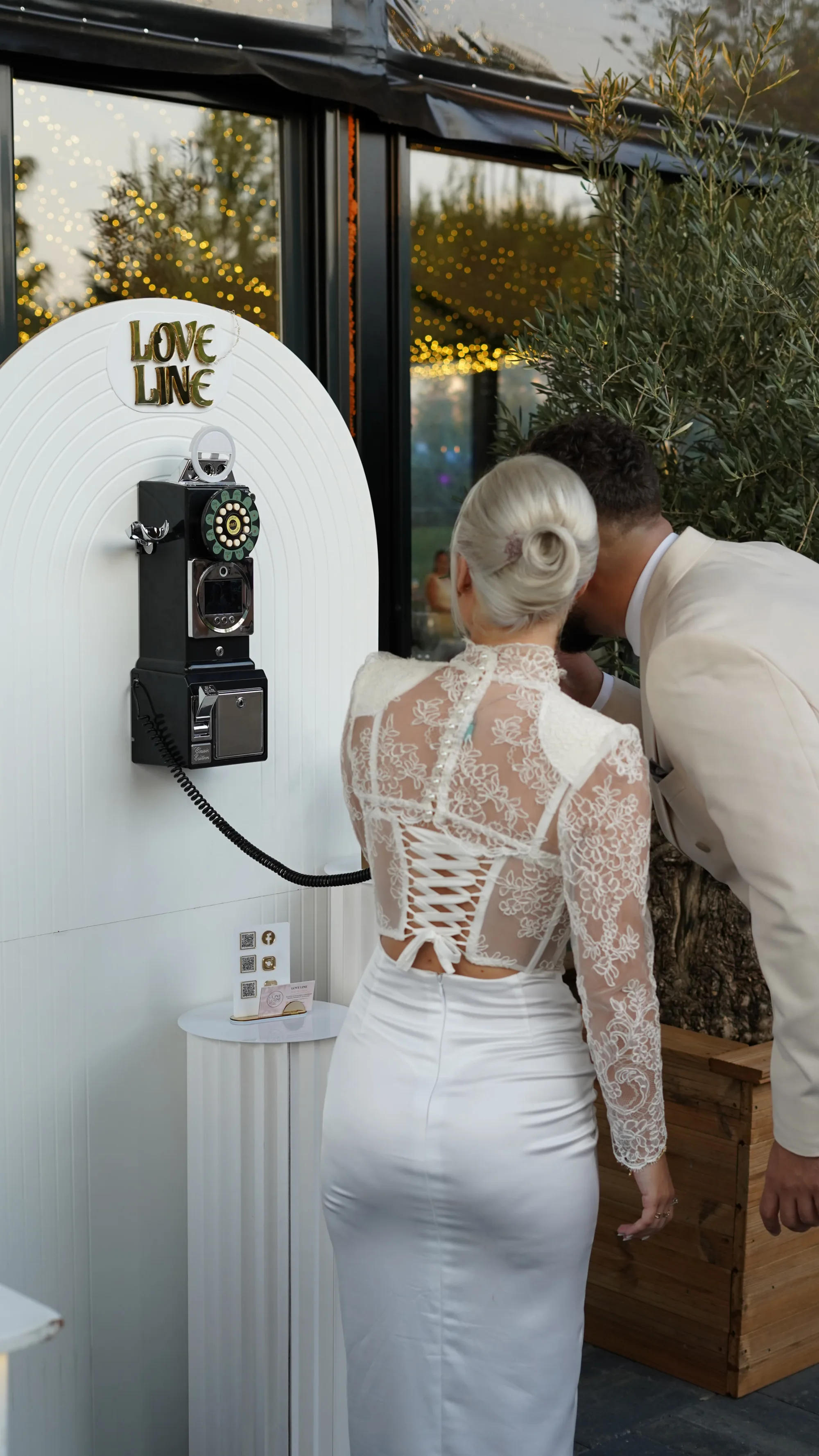 Mirii lasă un mesaj la telefonul vintage Love Line, montat pe o arcadă albă